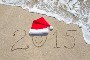 happy new year 2015 with smiley face in santa hat on sandy beach